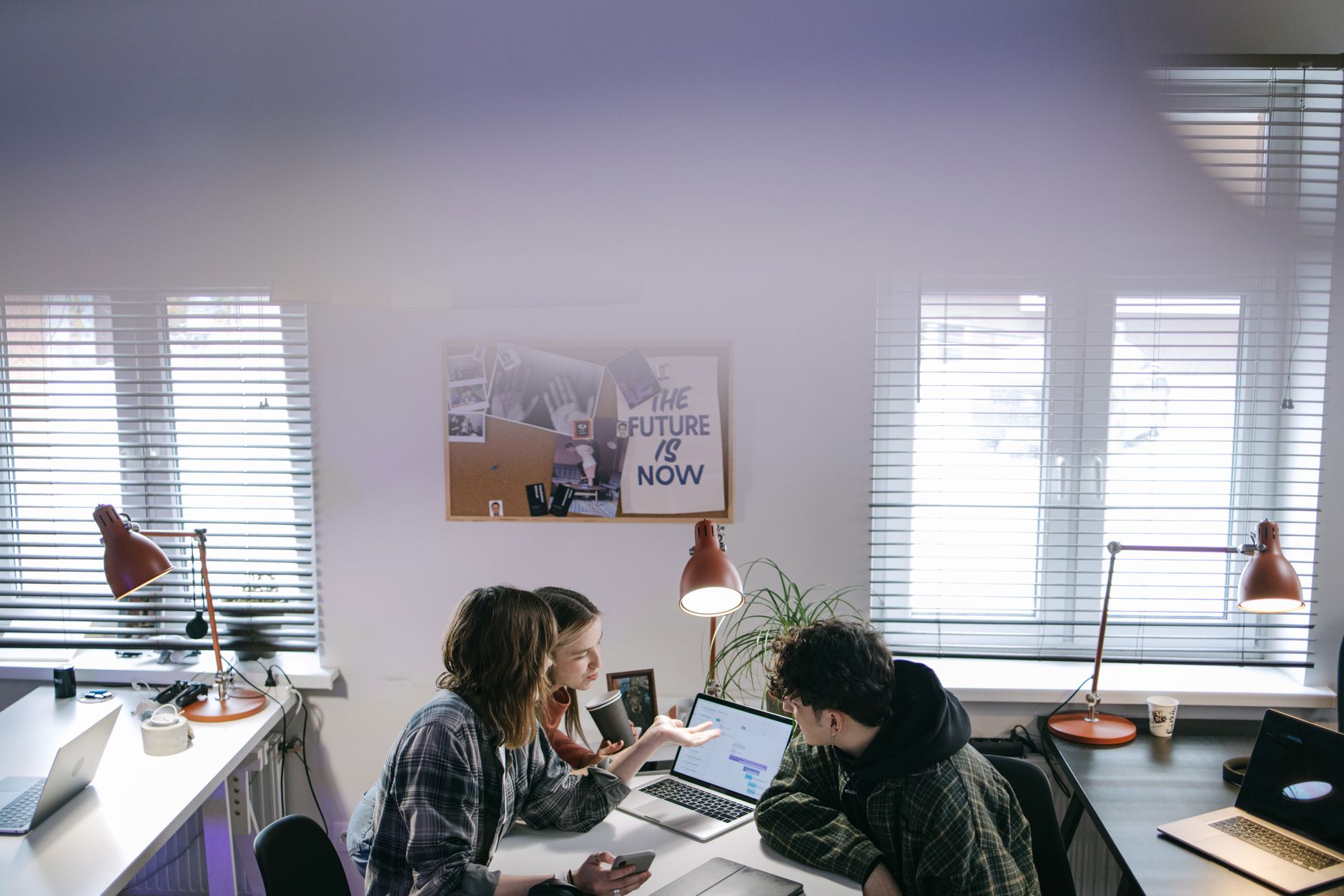A group of people discussing ideas around laptops in a bright, modern office space — illustrating: Virtualization for Small Business in Central Florida: Comparing Costs, Support, and Performance Solutions